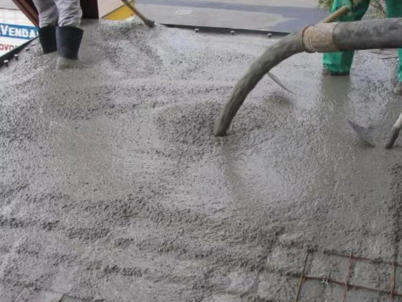 Mangote da bomba lançando concreto na laje enquanto a equipe espalha